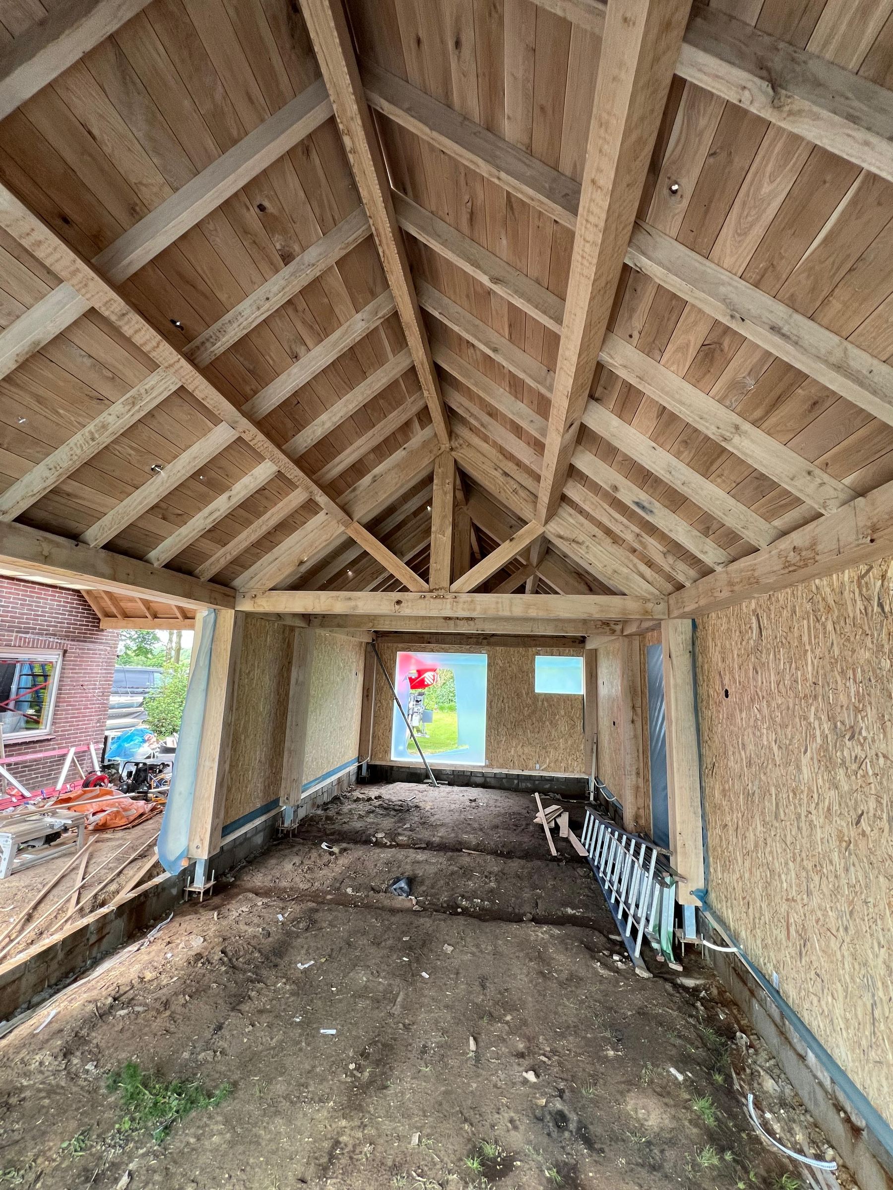 Houten constructie in aanbouw met de kap al op zijn plek