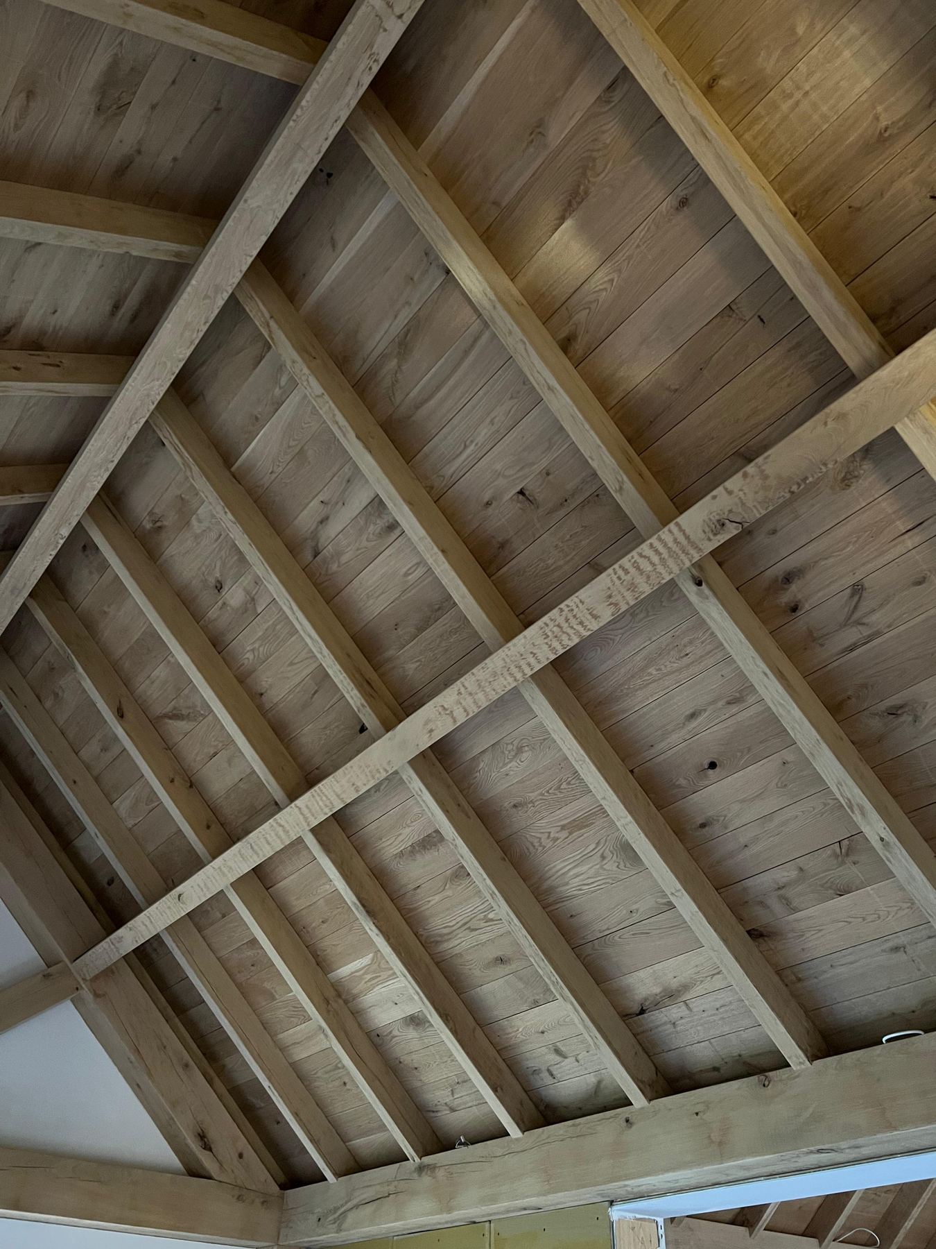 Onderaanzicht van een houten kapconstructie met gordingen en dakbeschot
